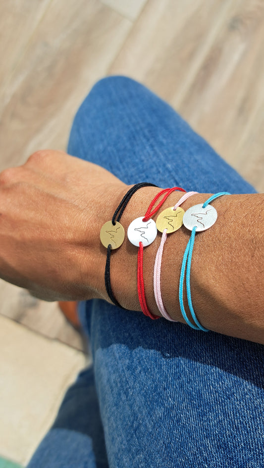 Portez l'emblème de Marseille au poignet. Un porte bonheur à offrir ou à garder en souvenir. Cordon ajustable, 4 couleurs au choix (noir, rouge, rose pâle et bleu pâle), médaillon gravé La bonne Mère en argent 925 recyclé ou plaqué or 18 carats 3 microns. Livraison possible dans toute la France