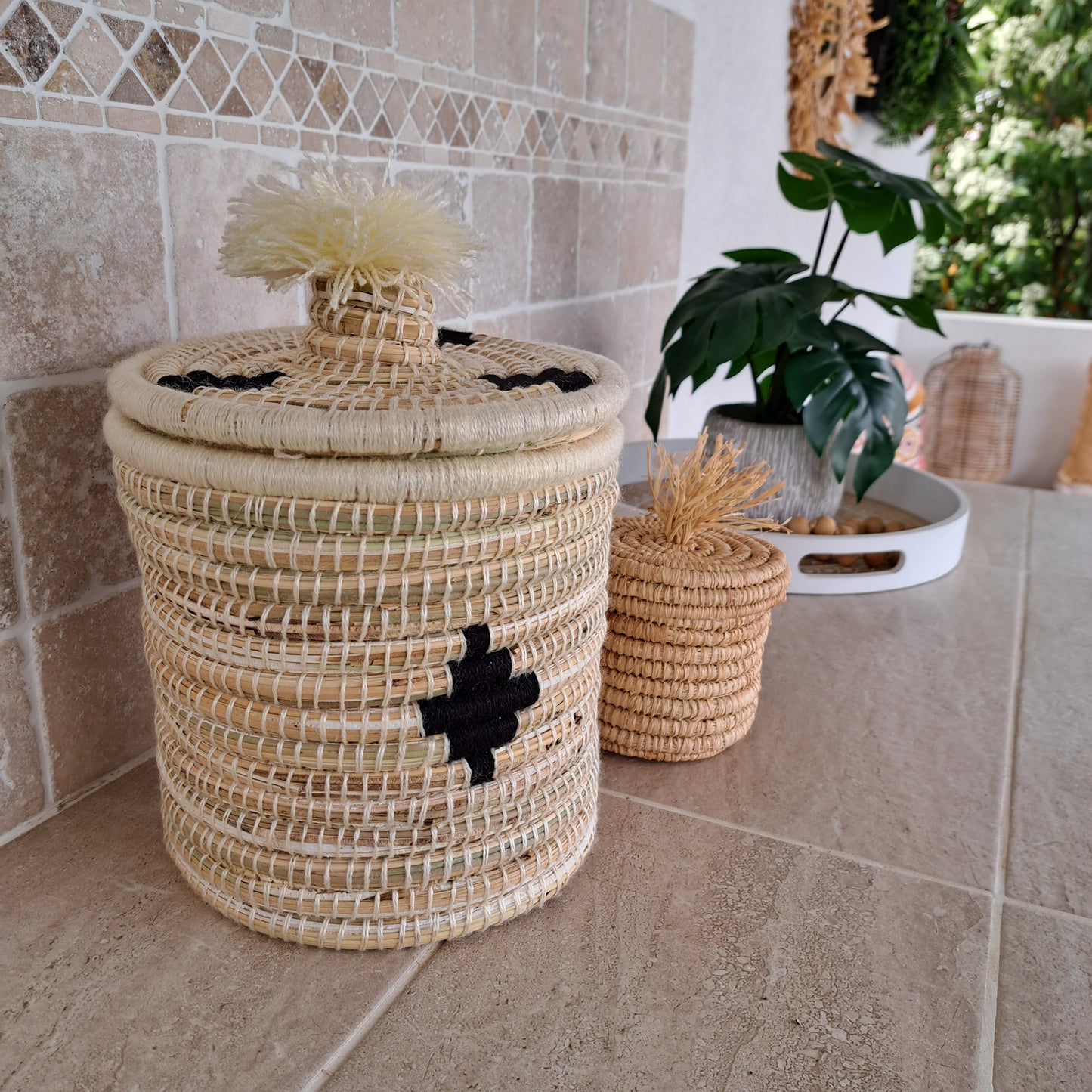 Panier berbère rond en osier et laine avec couvercle. Ce panier de fabrication artisanale au Maroc ajoutera un coté bohème à votre intérieur. Ces motifs noirs en forme de losanges ajoutent de la modernité. Avec une hauteur de 30cm, le panier berbère vous permettra de ranger ou cacher toutes les choses que vous souhaitez ranger avec élégance 